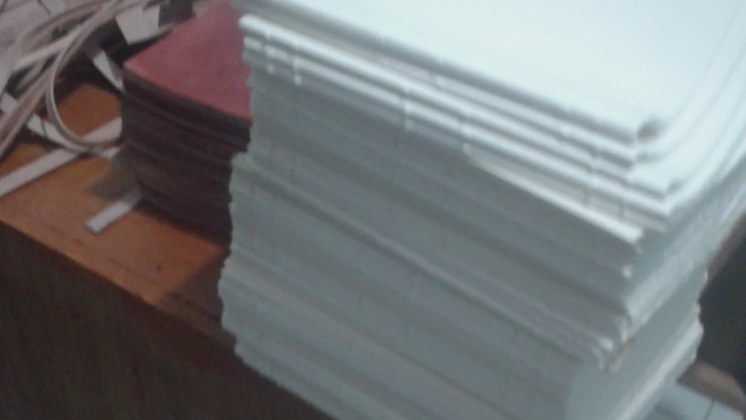 A stack of folded white paper on the workshop's wooden table