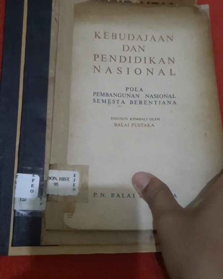 Hands holding an old book undergoing conservation for EFEO