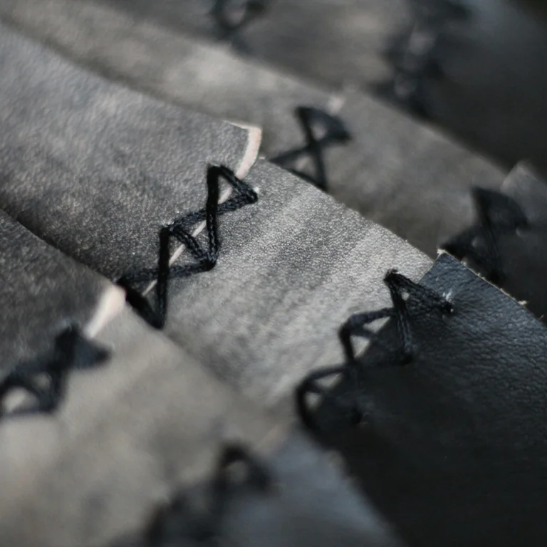 Black leather pieces joined with neat cross stitching.