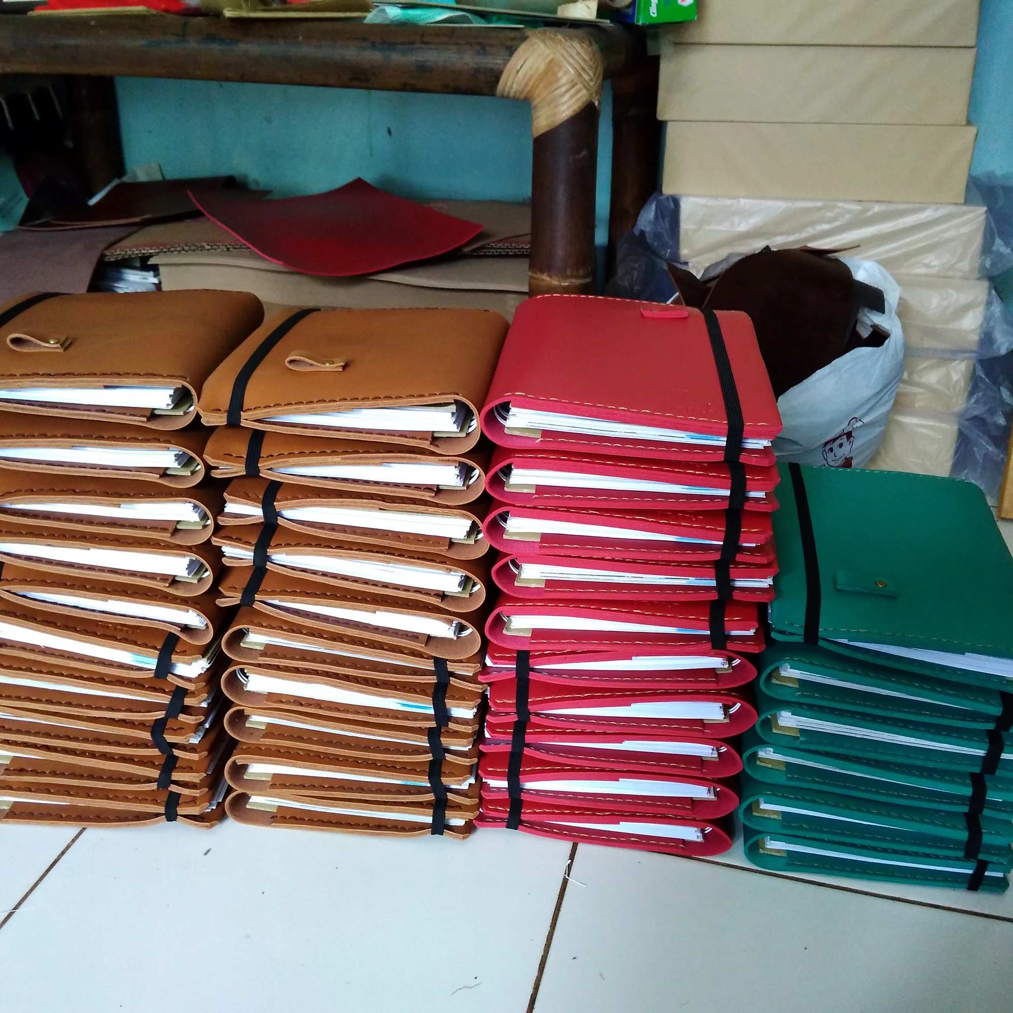 Tumpukan jurnal kulit berwarna di ruang kerja bengkel