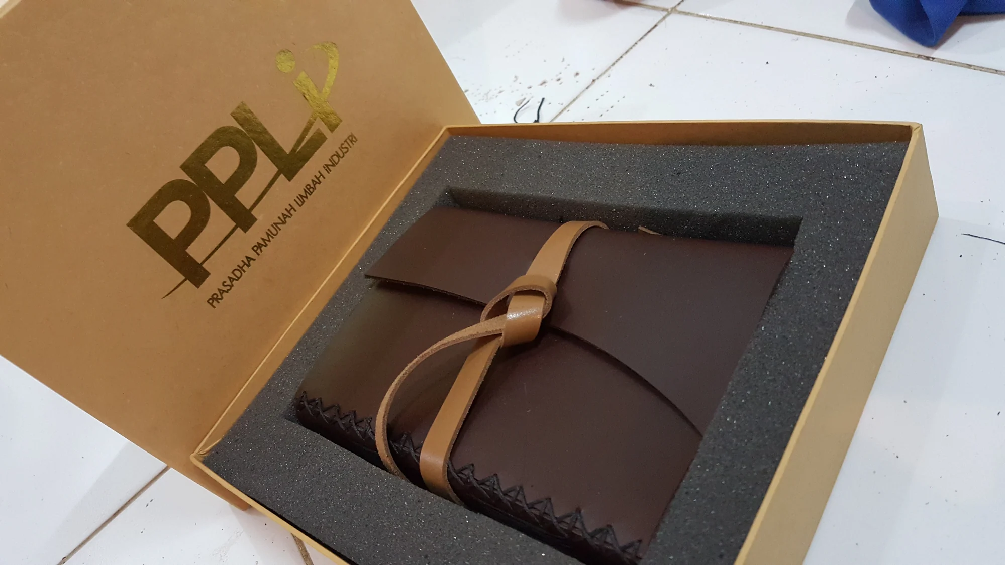 A strapped leather journal arranged inside a gift box