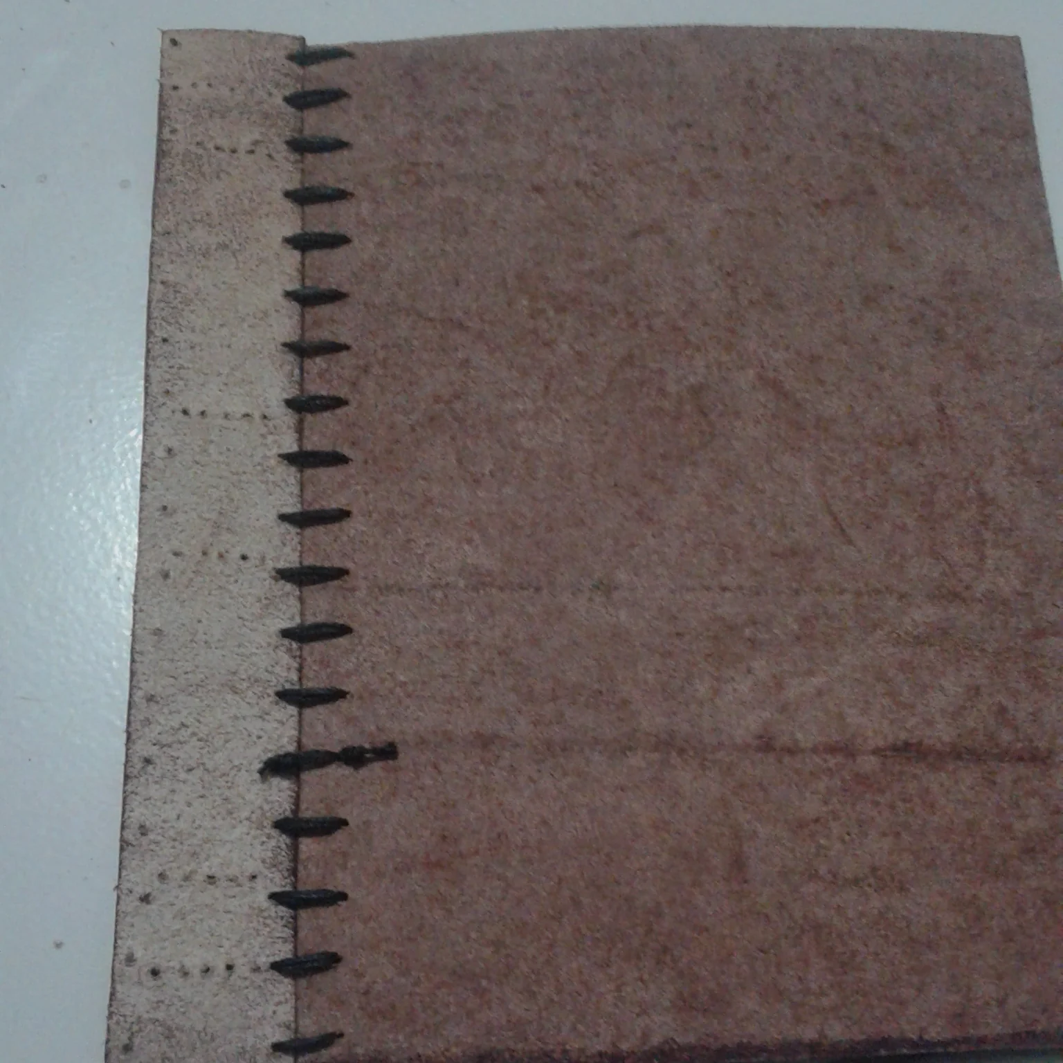 Leather journal cover with saddle stitching along the edge.
