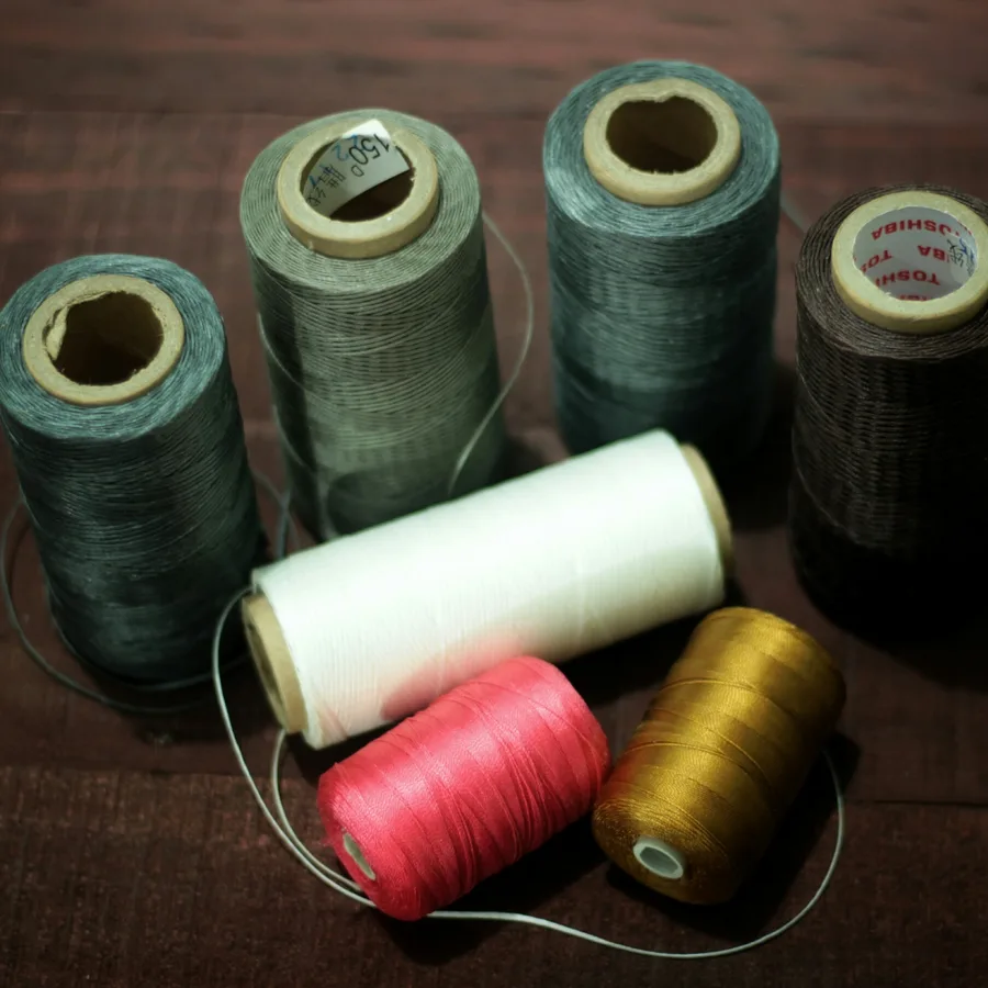 Spools of waxed thread in assorted colours on a wooden bench