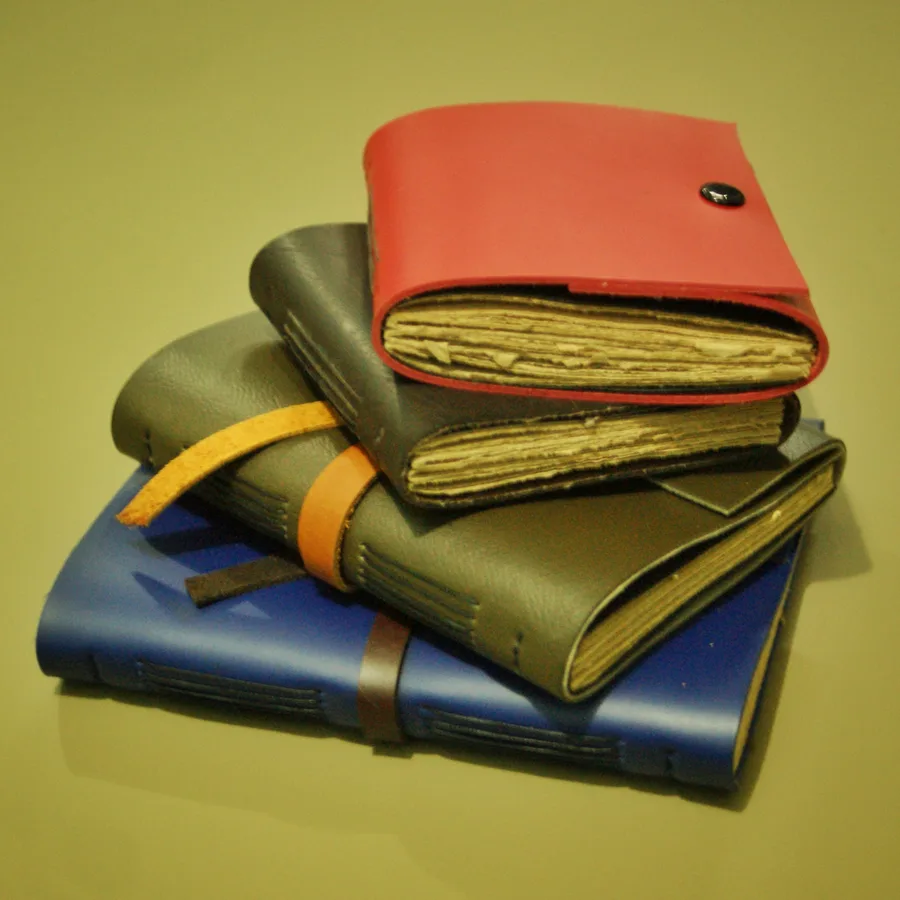 Three stacked leather journals with deckled paper edges