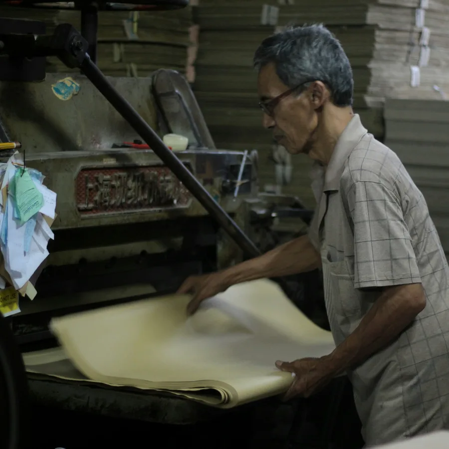 A worker operating a paper guillotine in the workshop