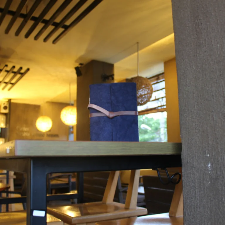 A blue leather journal with a strap closure placed on a restaurant table.