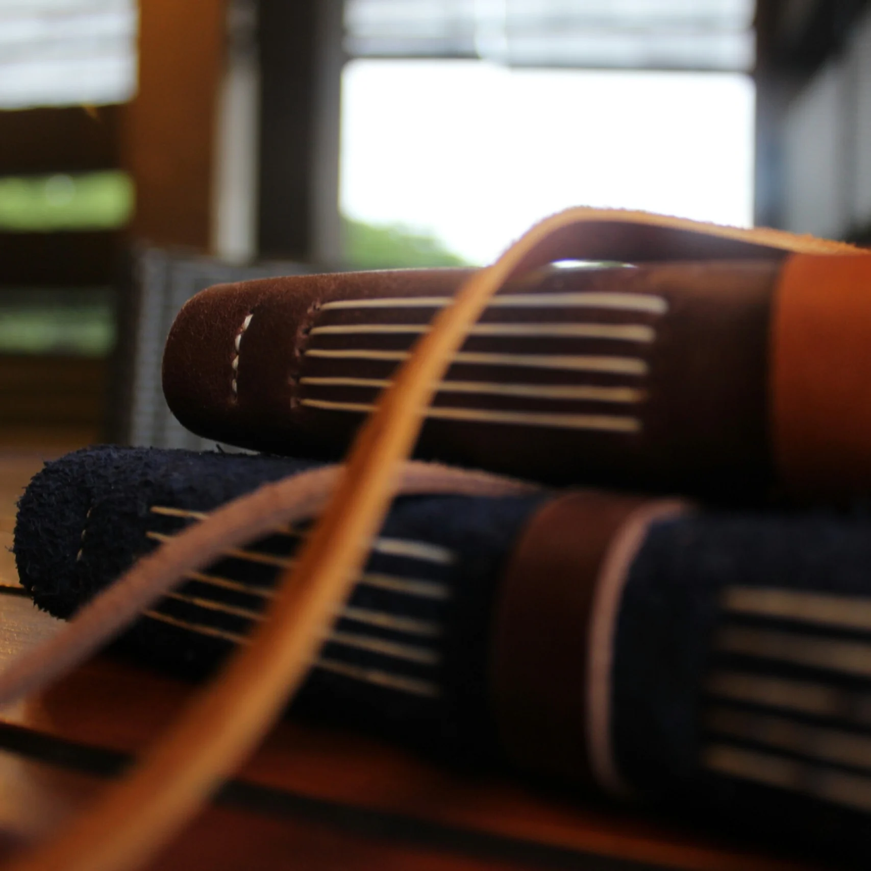 Two leather journals with coptic binding stacked on a wooden table.