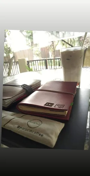 Story Instagram: dua jurnal kulit ditumpuk di meja kafe kayu bersama dua es kopi dan sebuah kantong kertas