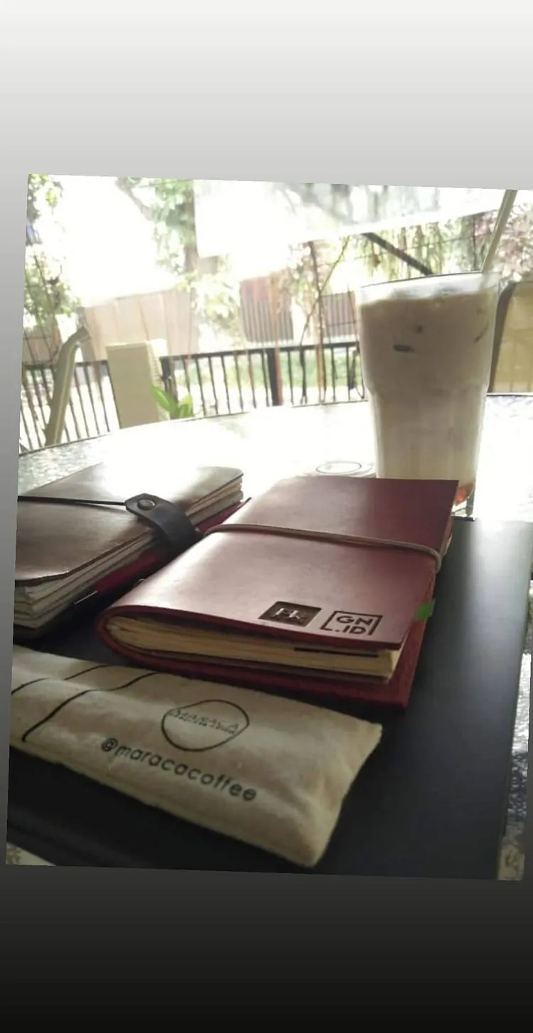 Story Instagram: dua jurnal kulit ditumpuk di meja kafe kayu bersama dua es kopi dan sebuah kantong kertas
