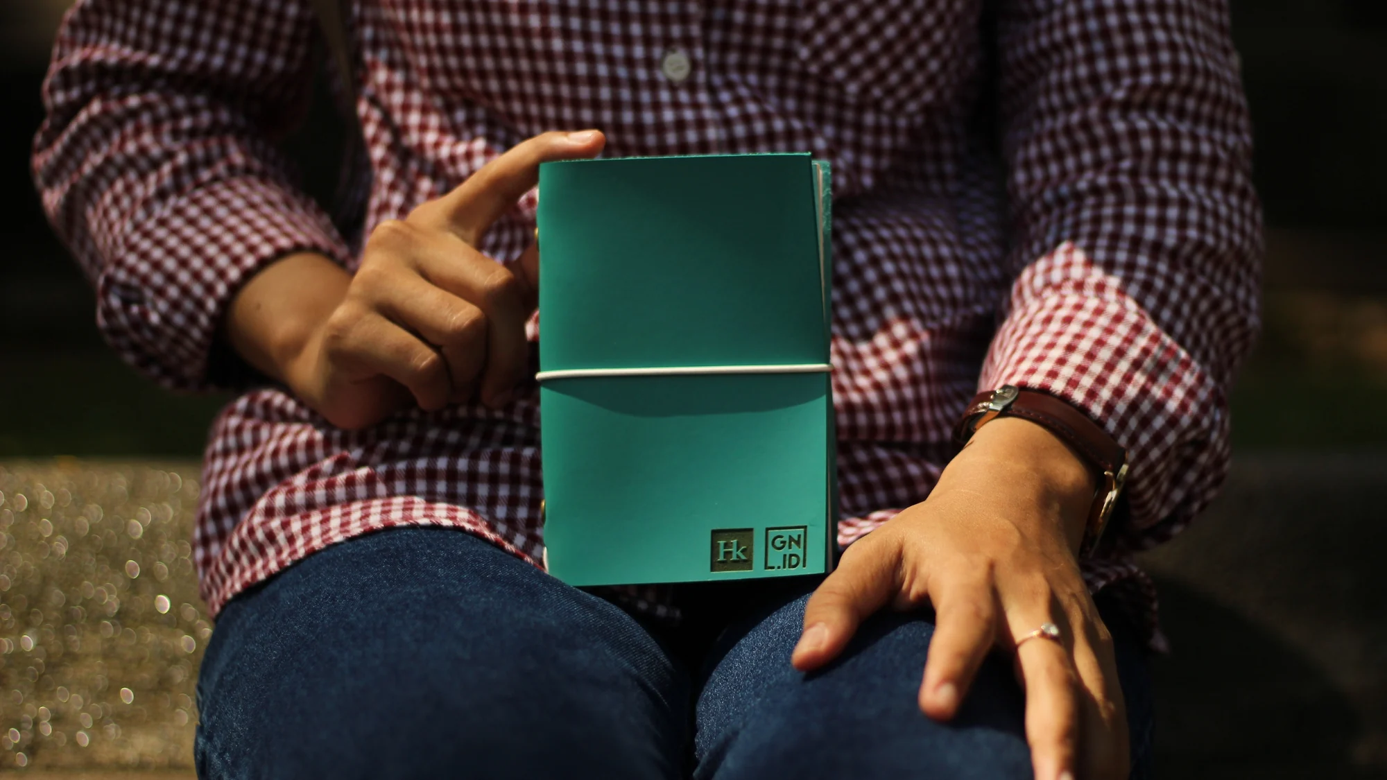 Someone holding a teal leather journal with an embossed logo