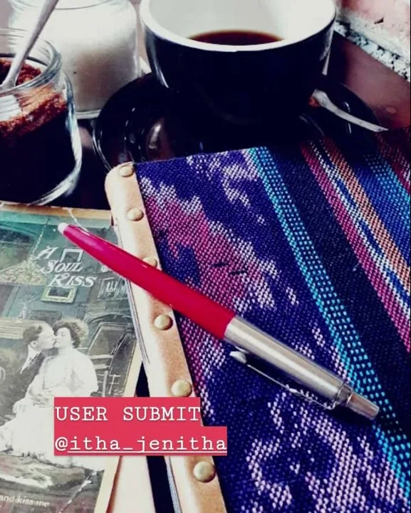 Jurnal bersampul kain tenun ungu dengan pena merah dan secangkir kopi