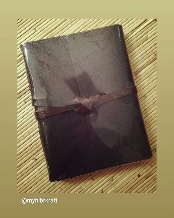 Jurnal kulit cokelat bertali lilit di atas anyaman bambu