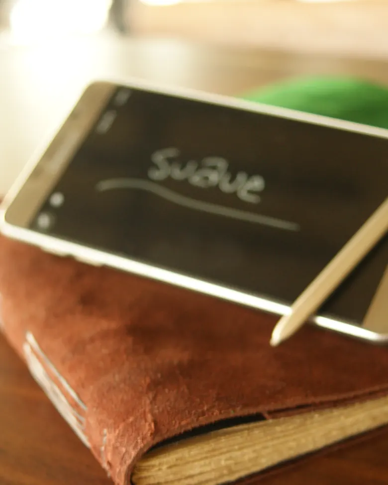 Smartphone di samping jurnal kulit suede bertekstur