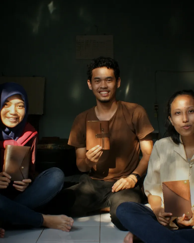 Tiga orang memegang jurnal kulit bersama-sama di acara open house bengkel