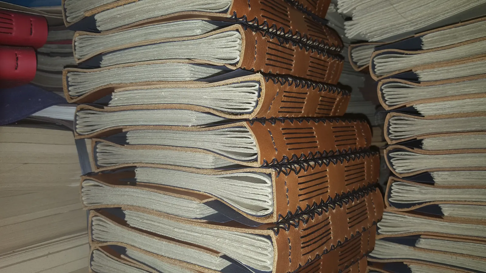 Stacked leather journals with exposed coptic-stitch spines, Hibrkraft's signature binding