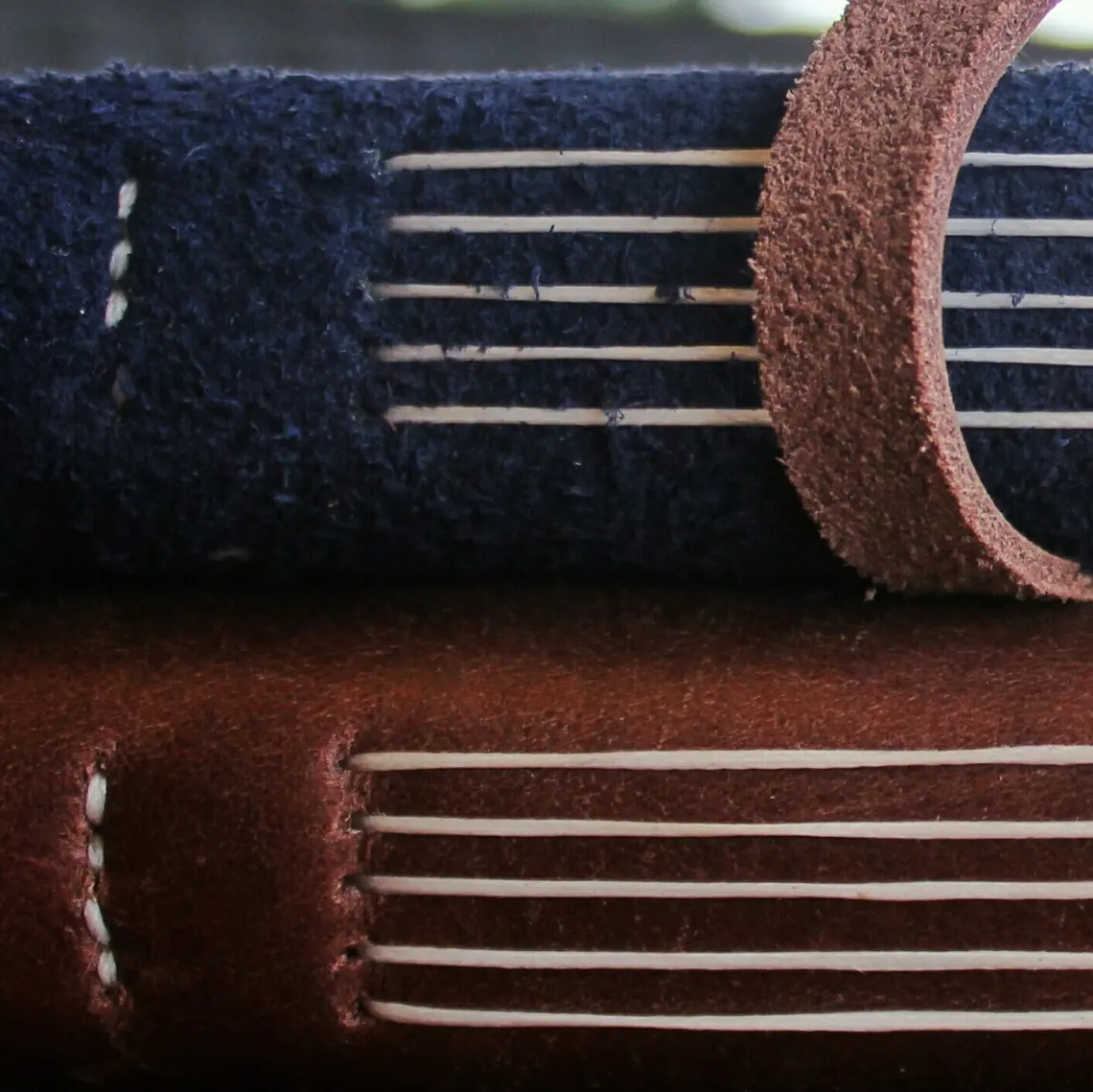 Close view of stacked leather journals showing the coptic-stitch spine construction
