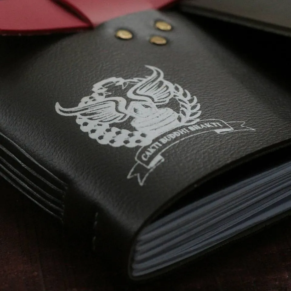 A close view of the Cakti Buddhi Bhakti logo embossed in leather