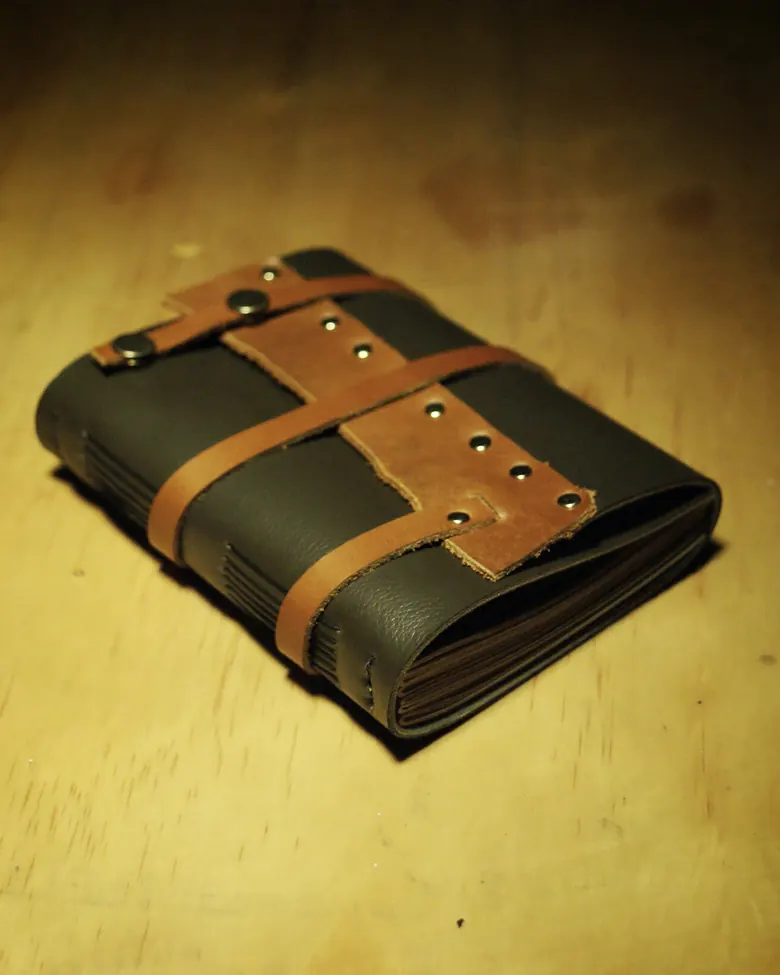 A Caesar model leather journal with a buckled strap closure.
