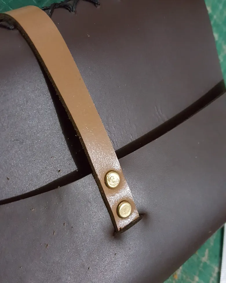 A brown leather journal with a brass fastener.