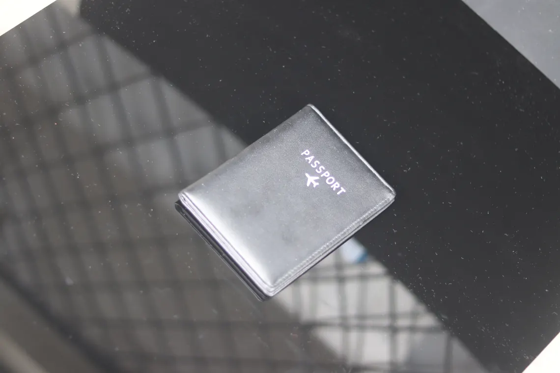 A black leather passport holder with no conspicuous logo, seen close up.