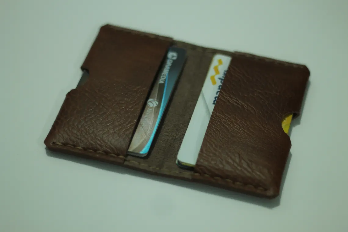 A brown leather card holder holding several business cards.