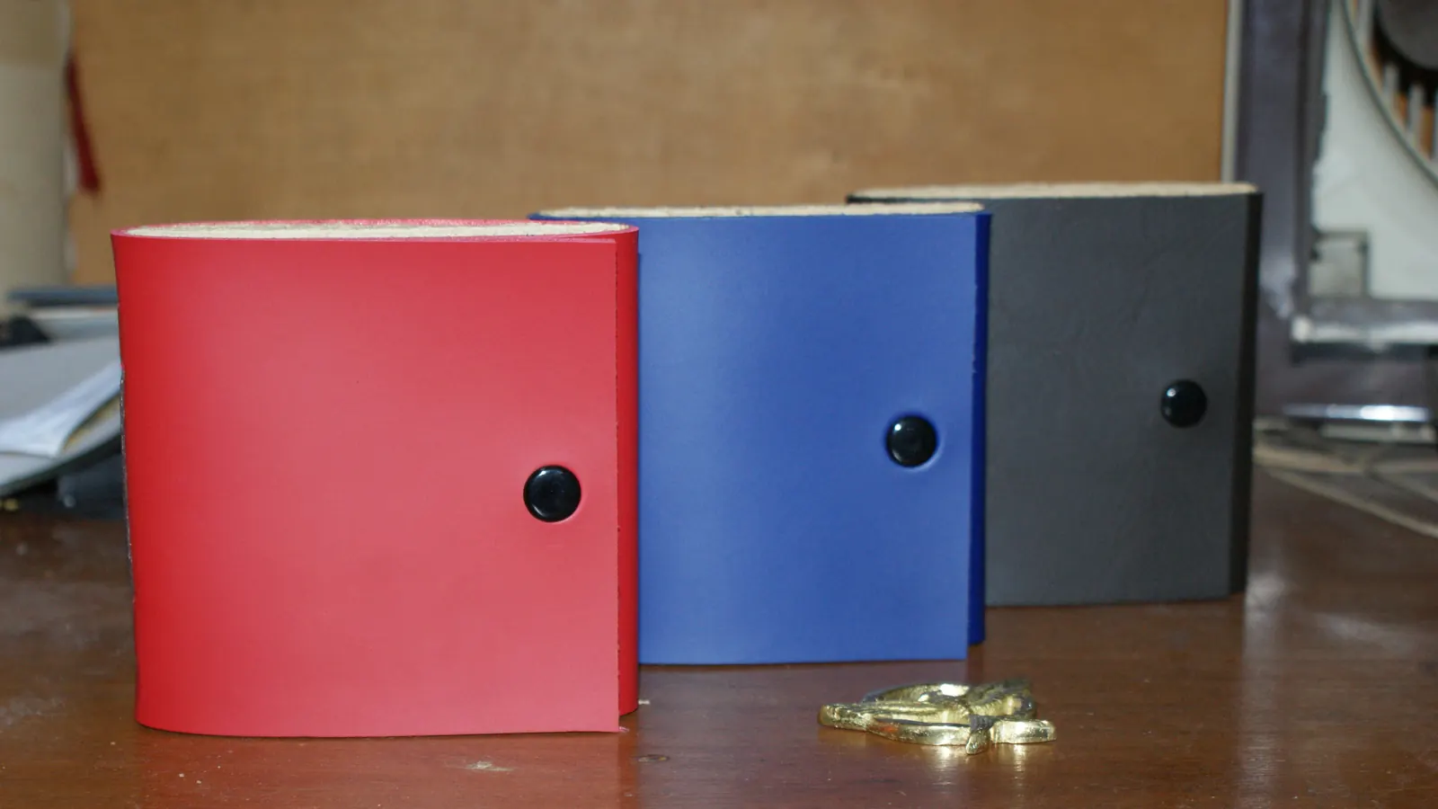 Three leather journals in red, blue and black, side by side