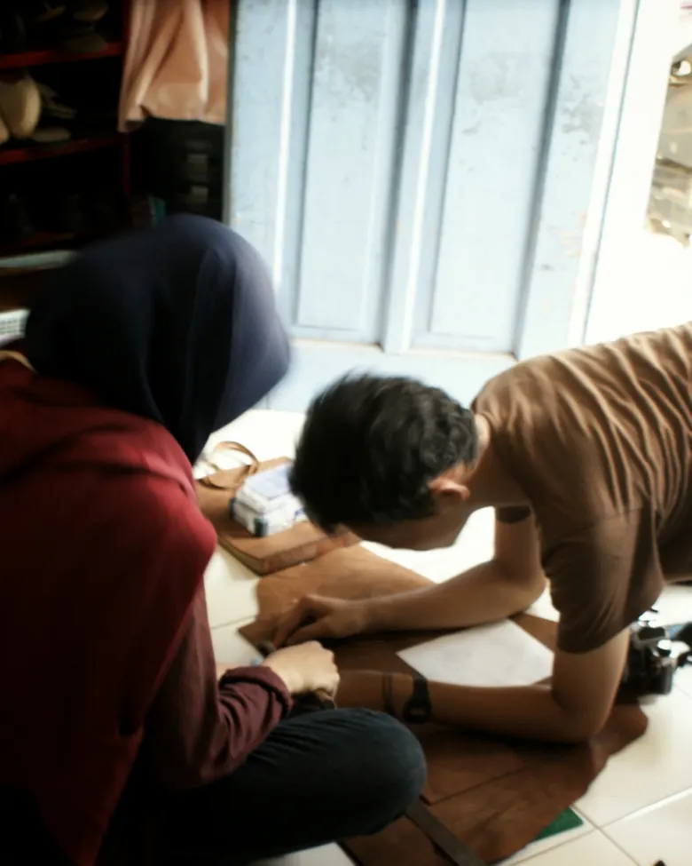 Beberapa orang mengerjakan lembar kulit bersama di sebuah acara openhouse.