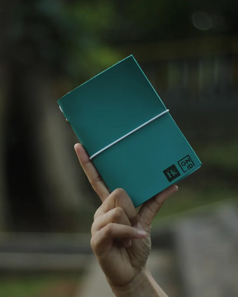 Tangan memegang jurnal kulit Hibrkraft warna teal