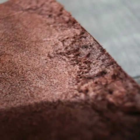 Permukaan kulit suede cokelat difoto dari dekat, memperlihatkan serat dan teksturnya