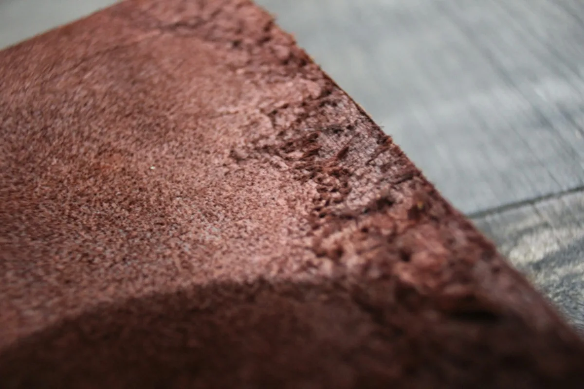 Permukaan kulit suede cokelat difoto dari dekat, memperlihatkan serat dan teksturnya