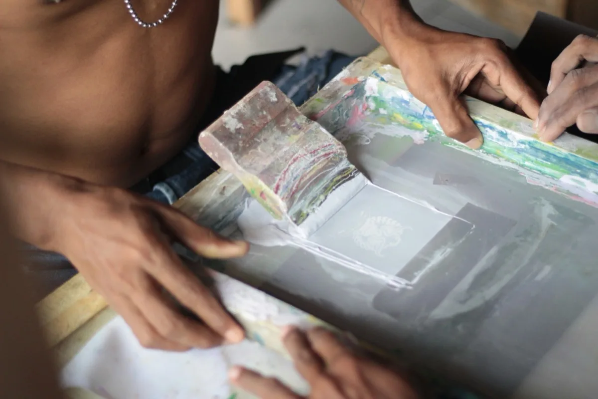Proses sablon dengan rakel di atas screen di bengkel