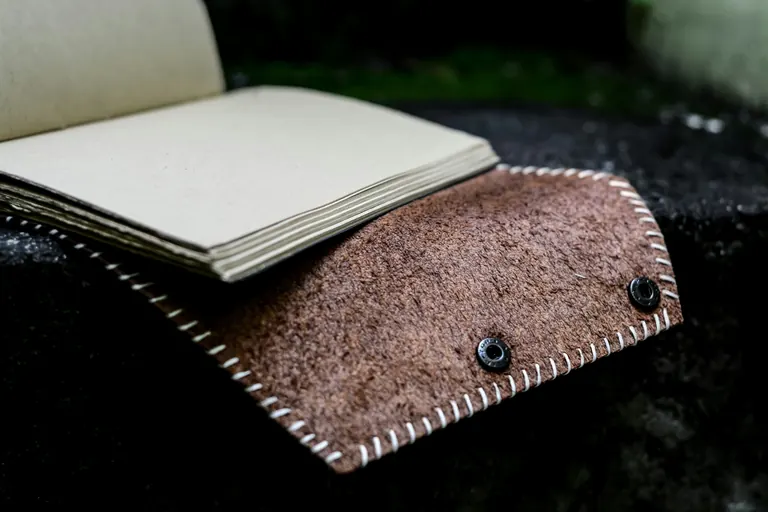 Buku catatan kulit suede dengan jahitan putih, halaman polos tanpa struktur cetak