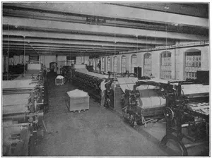 FOURDRINIER MACHINES, CRANE & CO. A good view of the surface-sizing vat is obtained in the machine on the right hand. The paper is being slit just before its introduction into the vat.