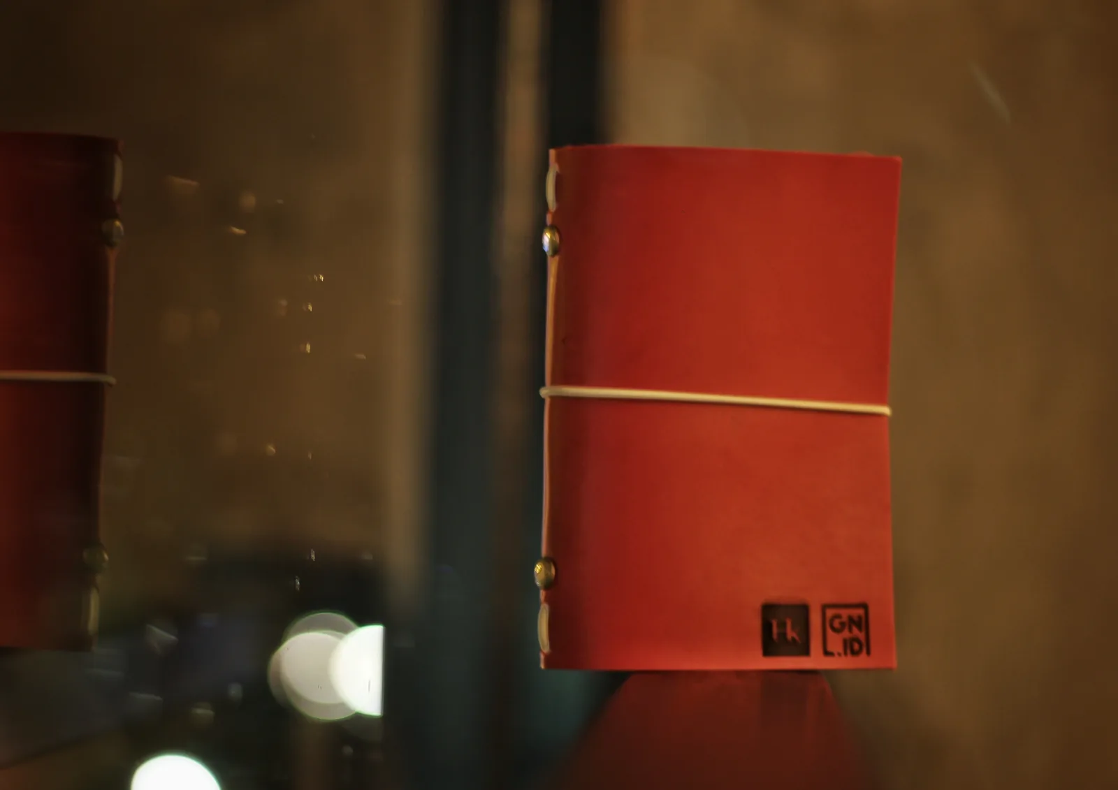 Pormenor de uma capa de couro vermelho com dois carimbos quadrados lado a lado: Hk e GN.ID