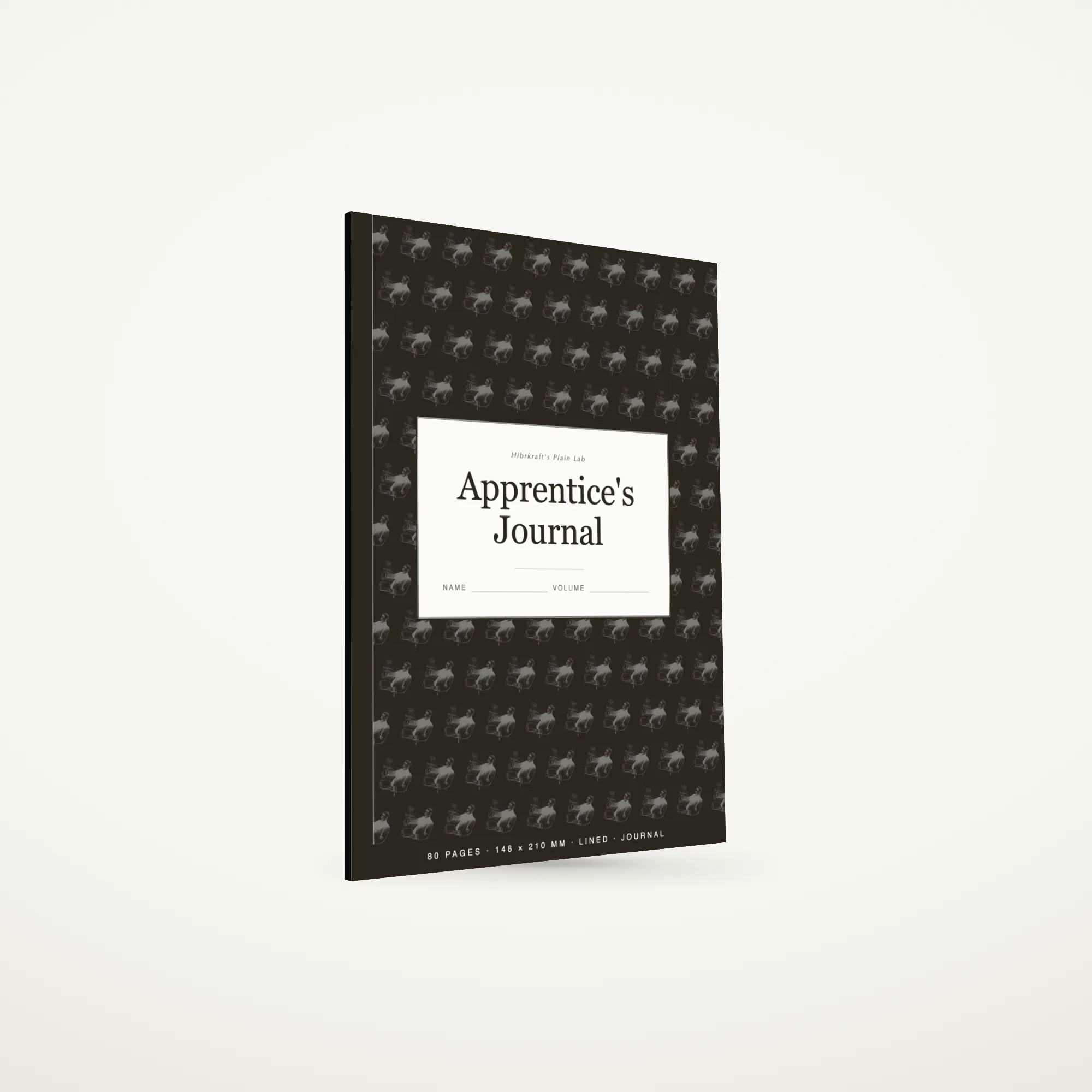 Apprentice's Journal A5 tertutup, berdiri di atas permukaan polos, sebuah bidang ilustrasi berulang di sampulnya, sebuah plat label krem dekat bagian tengahnya yang membawa judulnya, sebuah pita jilid sempit di sepanjang punggungnya.