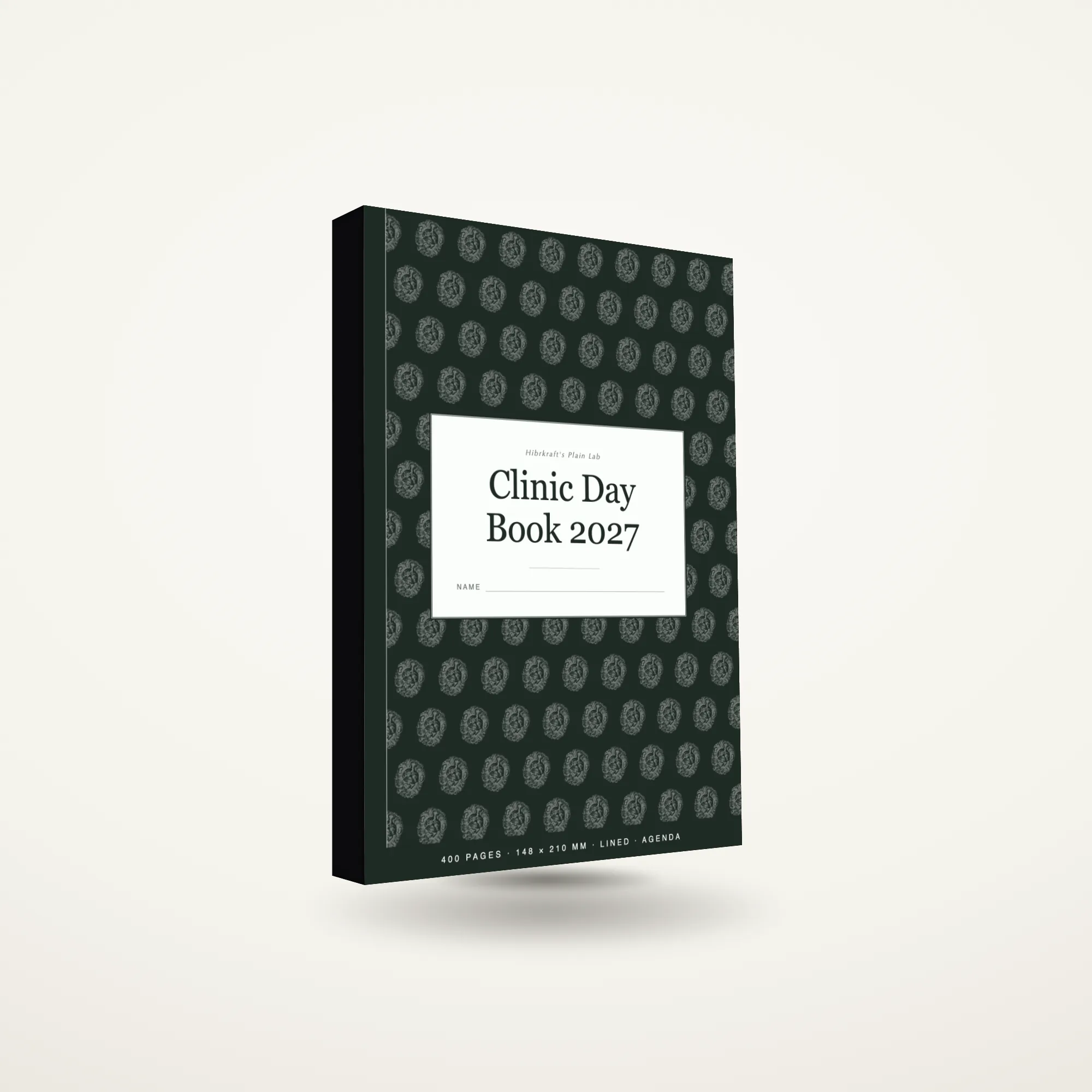 A5 Clinic Day Book 2027 standing closed on a plain surface, dark cover with a cross and stethoscope motif, about twenty-three millimetres thick.