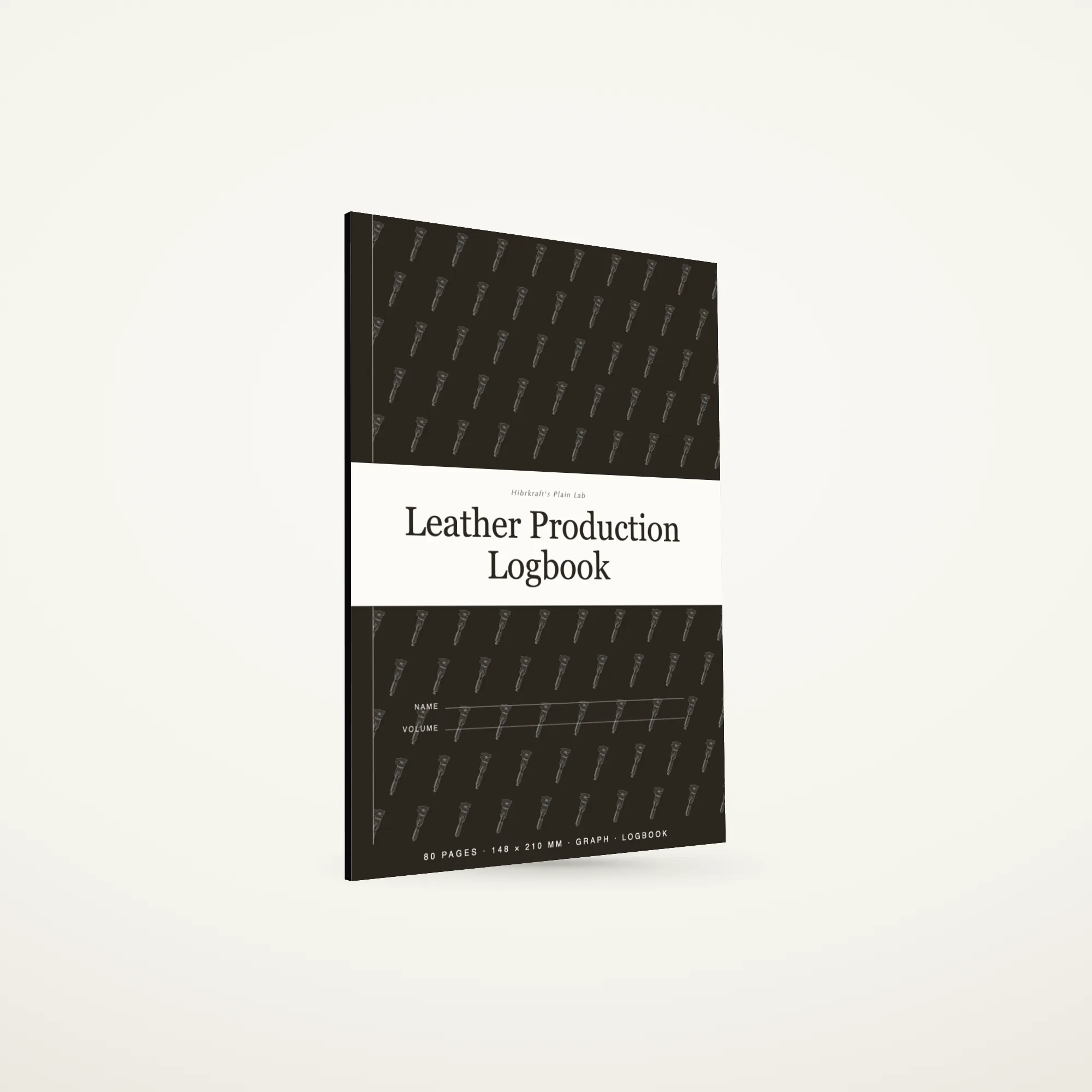 Leather Production Logbook A5 de pé e fechado sobre uma bancada, capa com um motivo de ferramentas, um volume fino com menos de cinco milímetros de espessura.